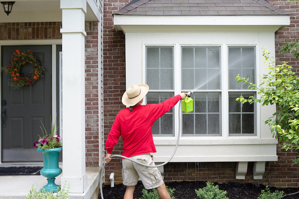 man pressure washing house