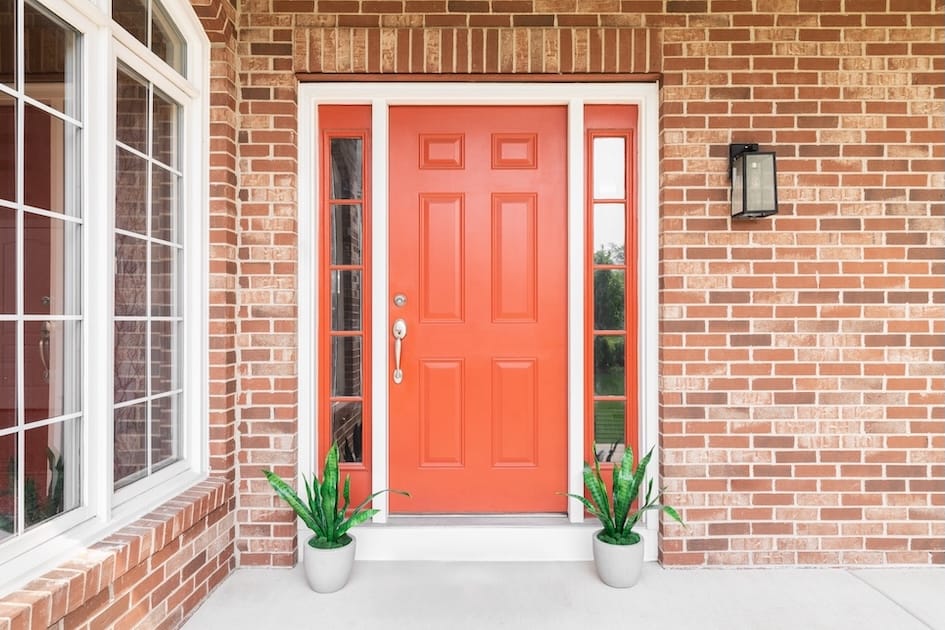 red front door with two potted plants